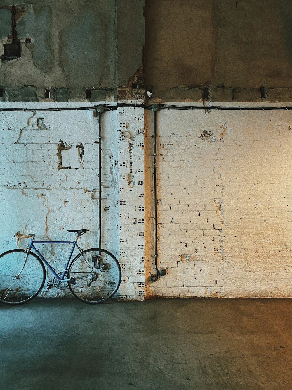 blue city bike leaning on white wall