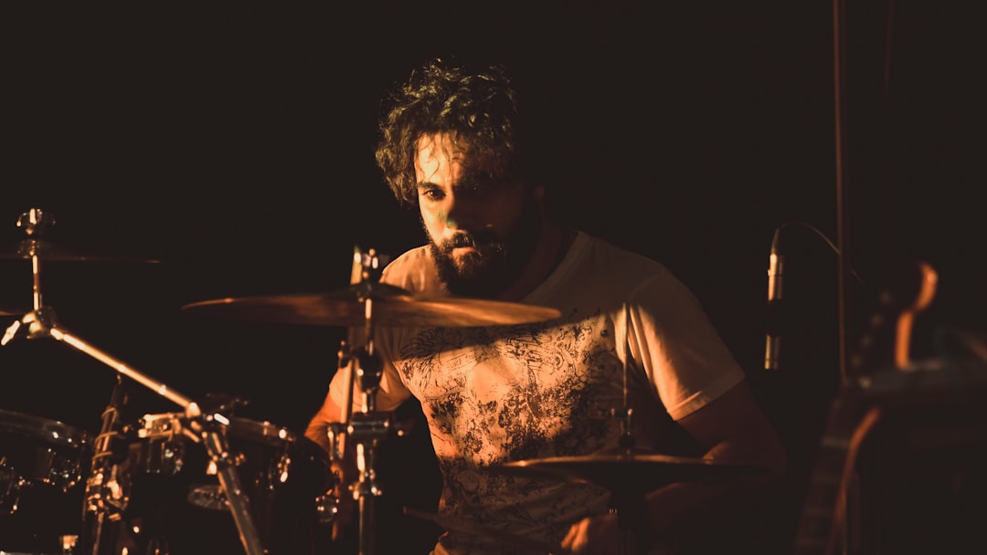 man in white shirt playing drum set