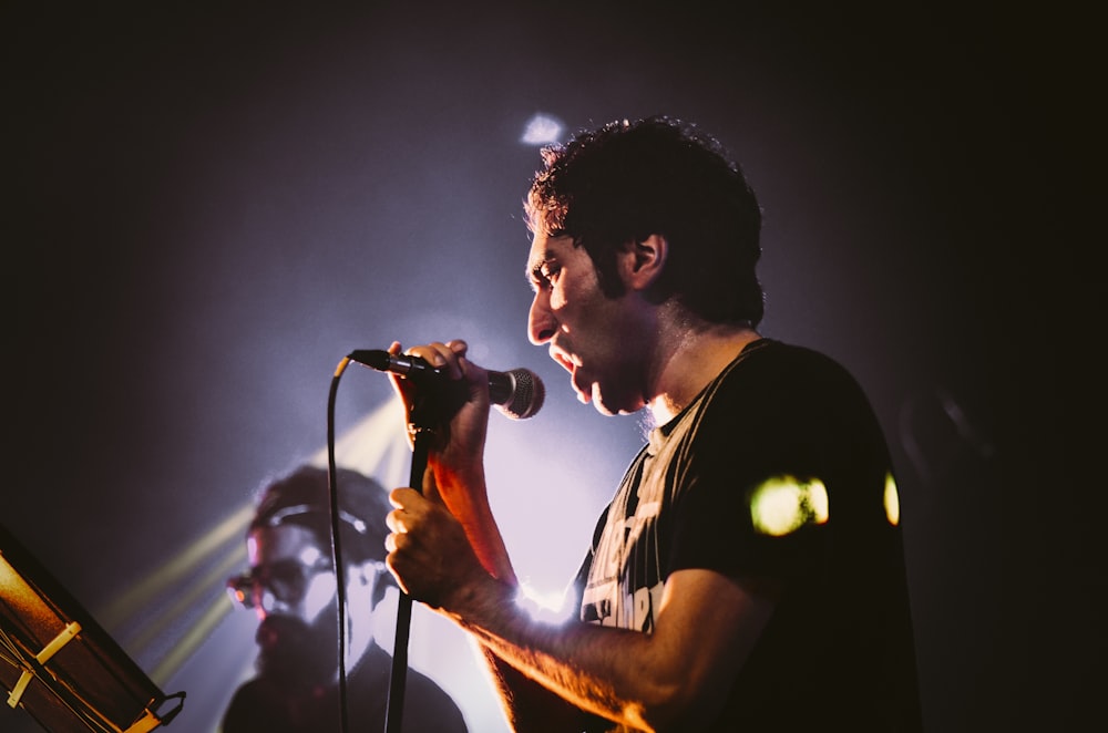 man in black and white crew neck t-shirt singing