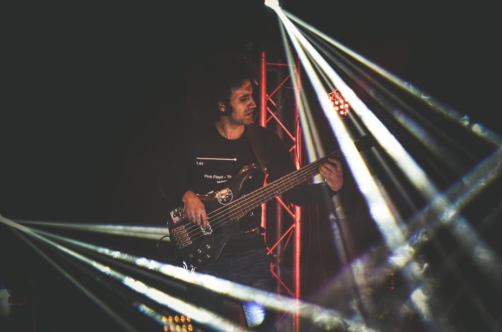 man in black crew neck t-shirt playing guitar