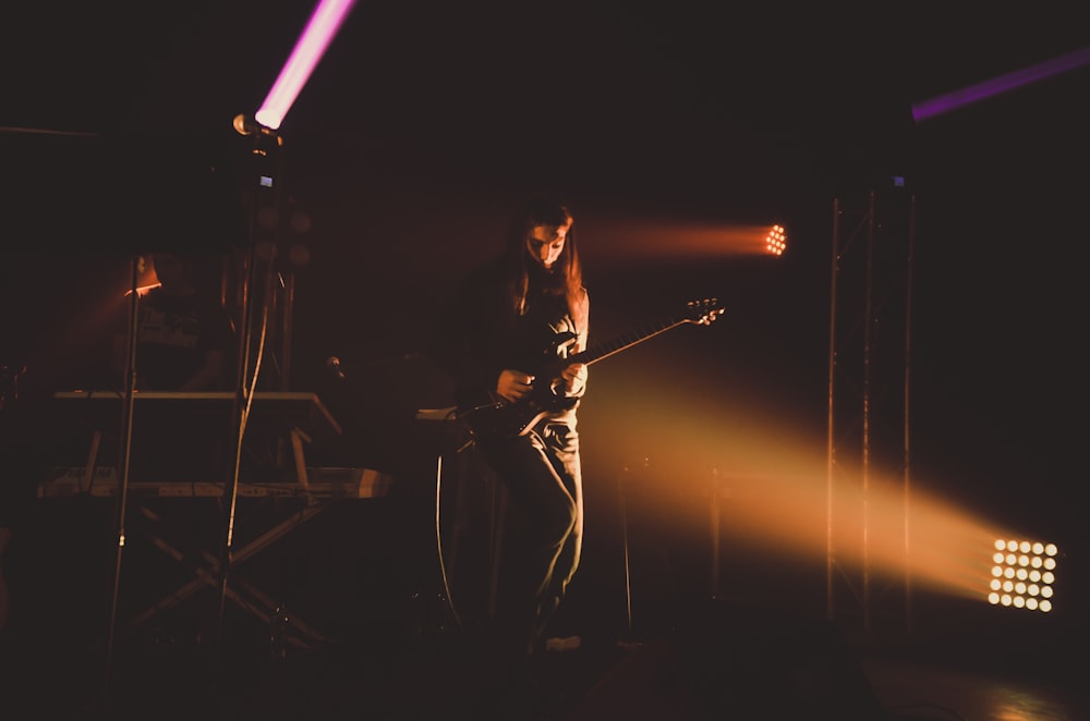 man in black tank top playing guitar on stage