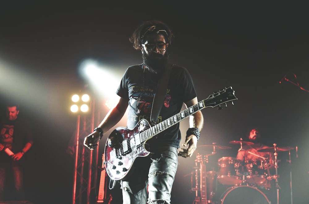 man in black crew neck t-shirt playing electric guitar