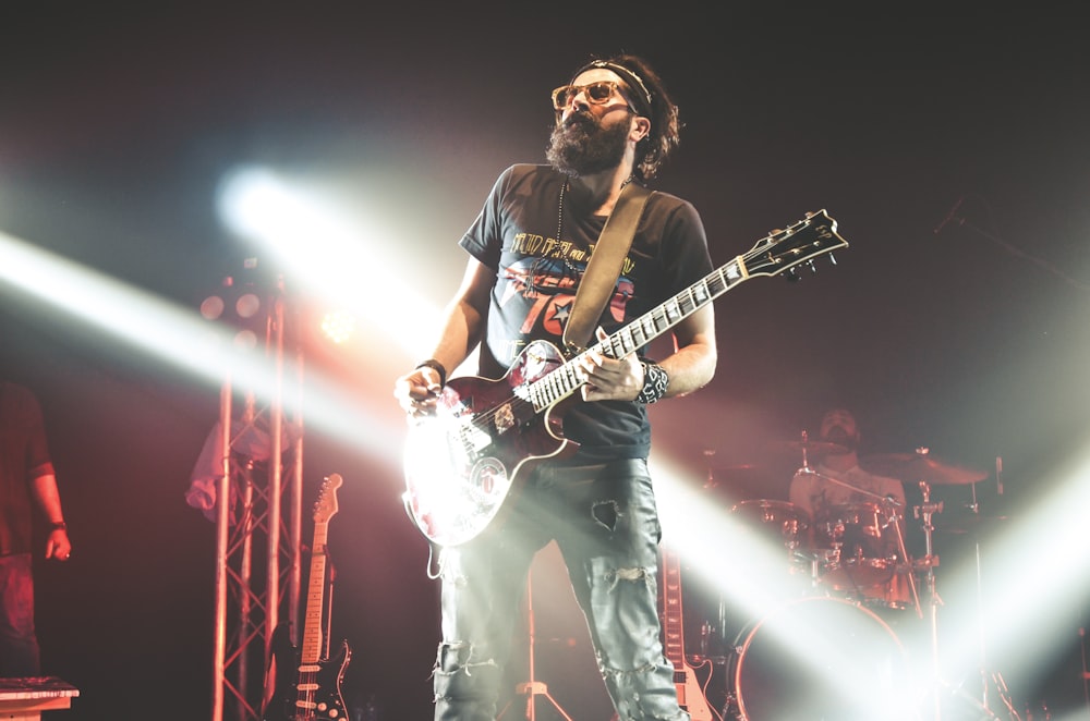 man in black crew neck t-shirt playing electric guitar