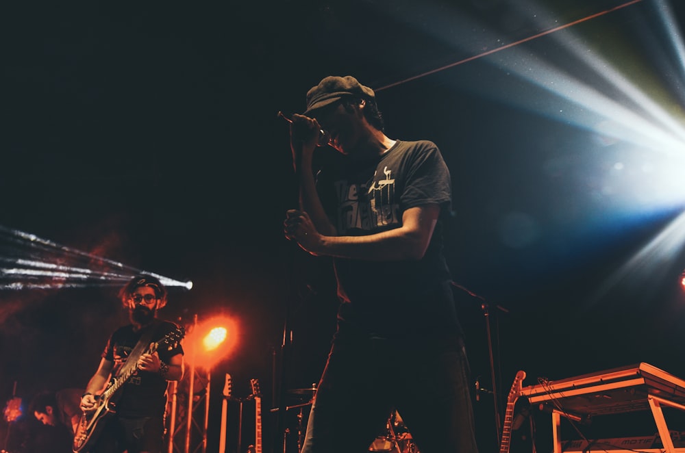 man in black t-shirt singing on stage