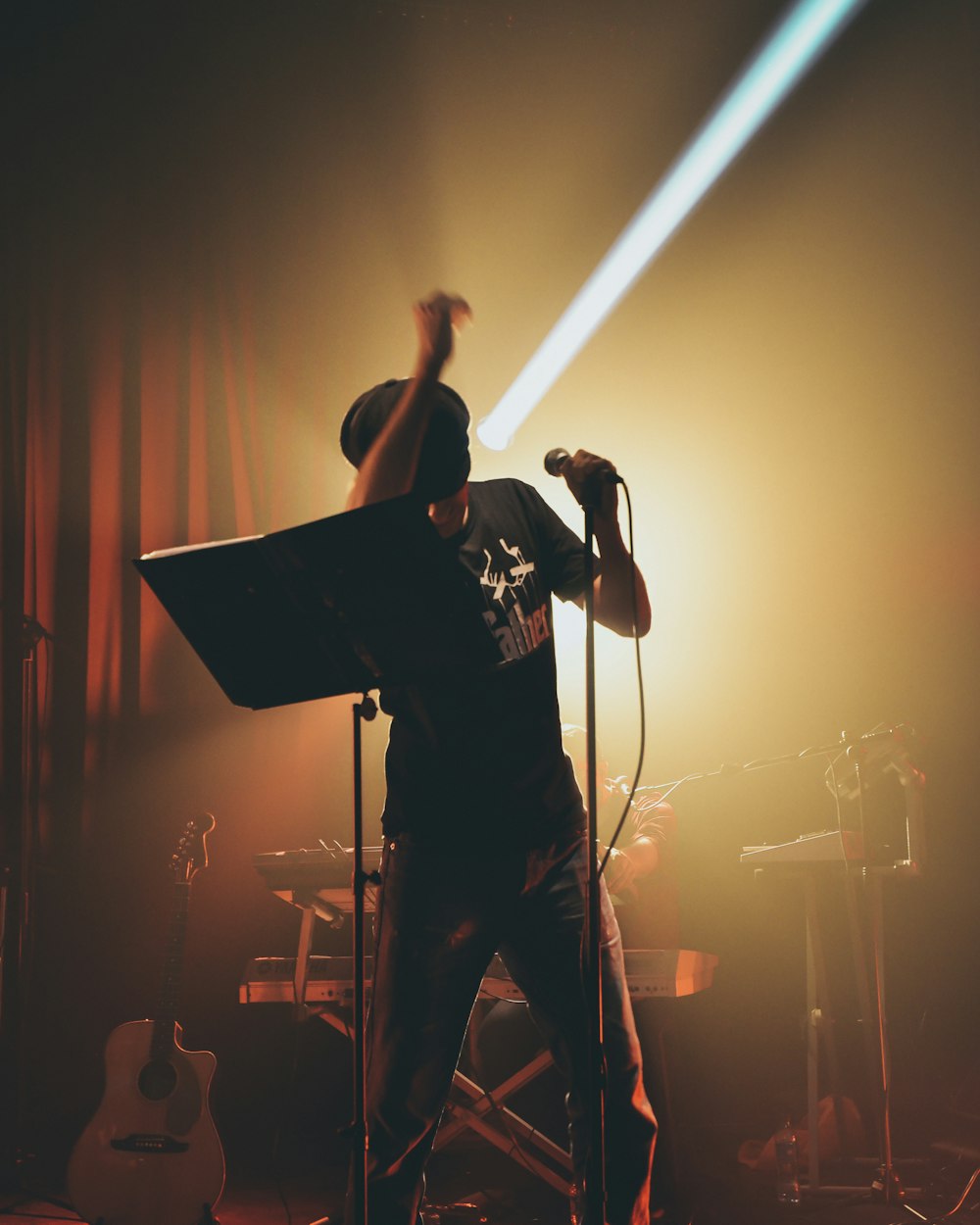 Mann im schwarzen T-Shirt singt auf der Bühne