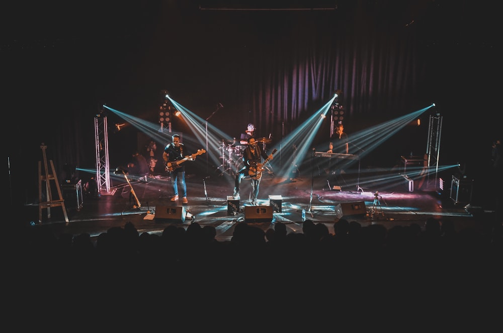 people standing on stage with lights turned on during night time