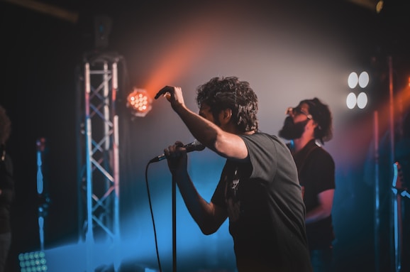 man in black shirt singing on stage