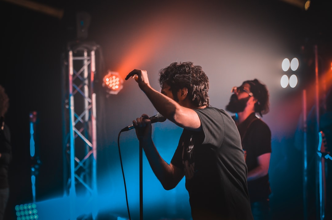 man in black shirt singing on stage