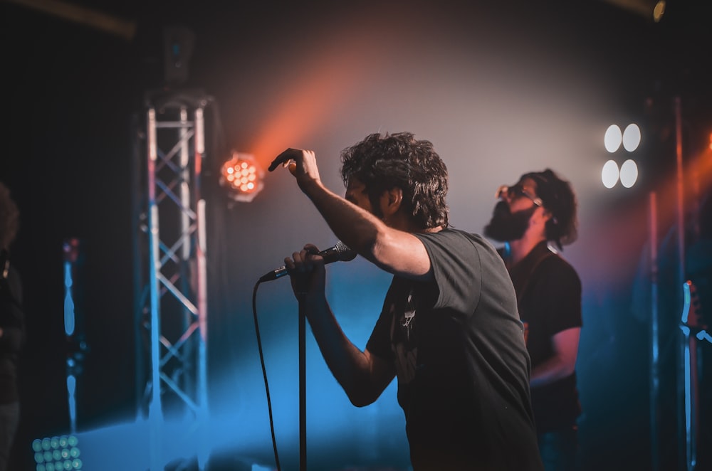 man in black shirt singing on stage