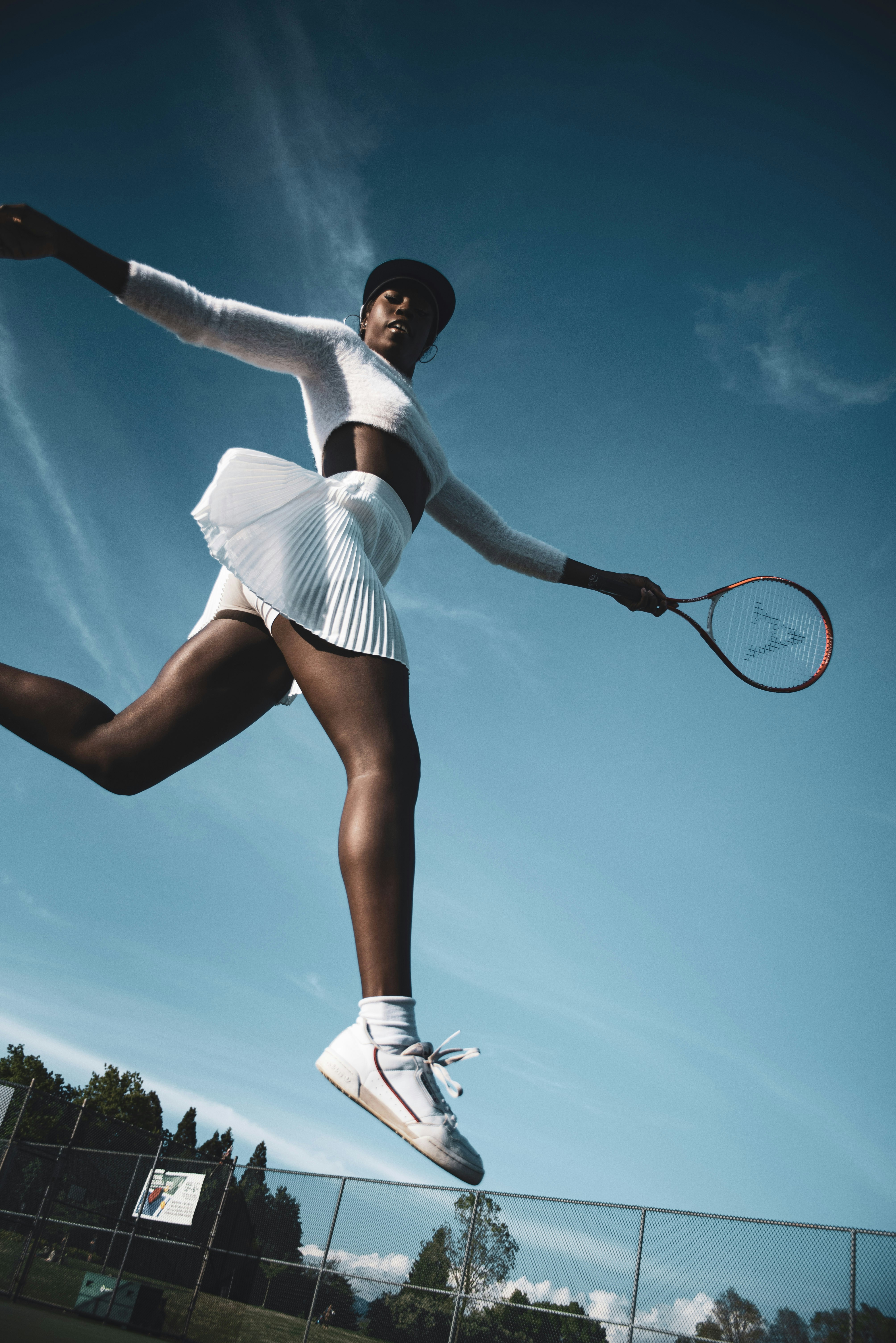 woman in white dress holding black and white tennis racket