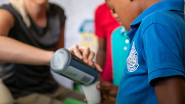 Volunteers pouring drinks into children's glasses