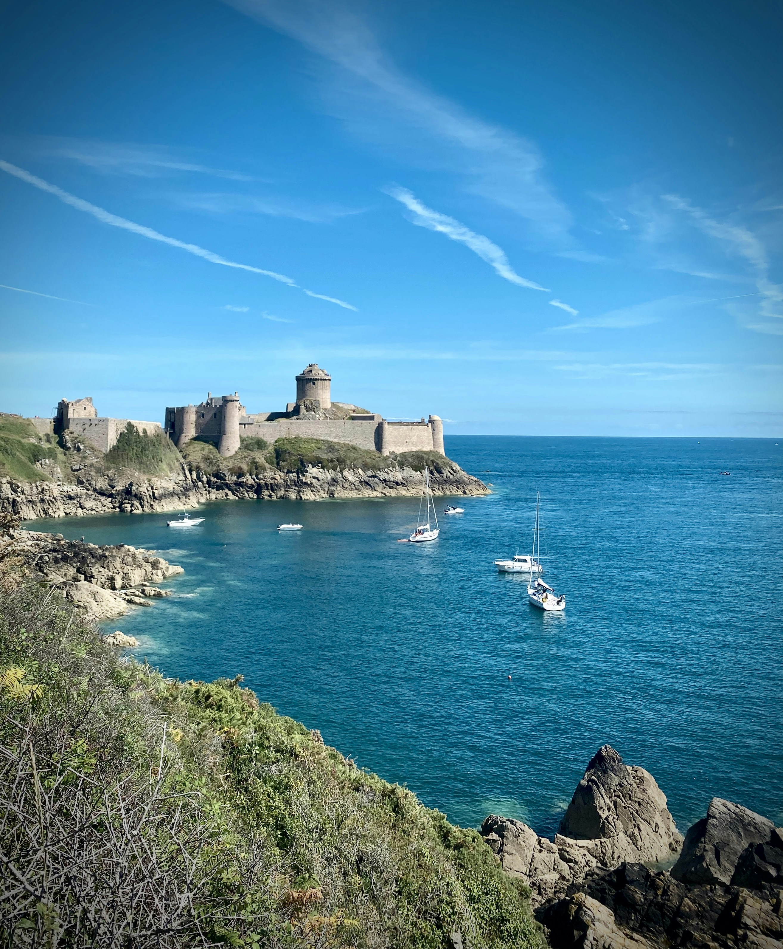 white boat on sea near gray concrete building under blue sky during daytime