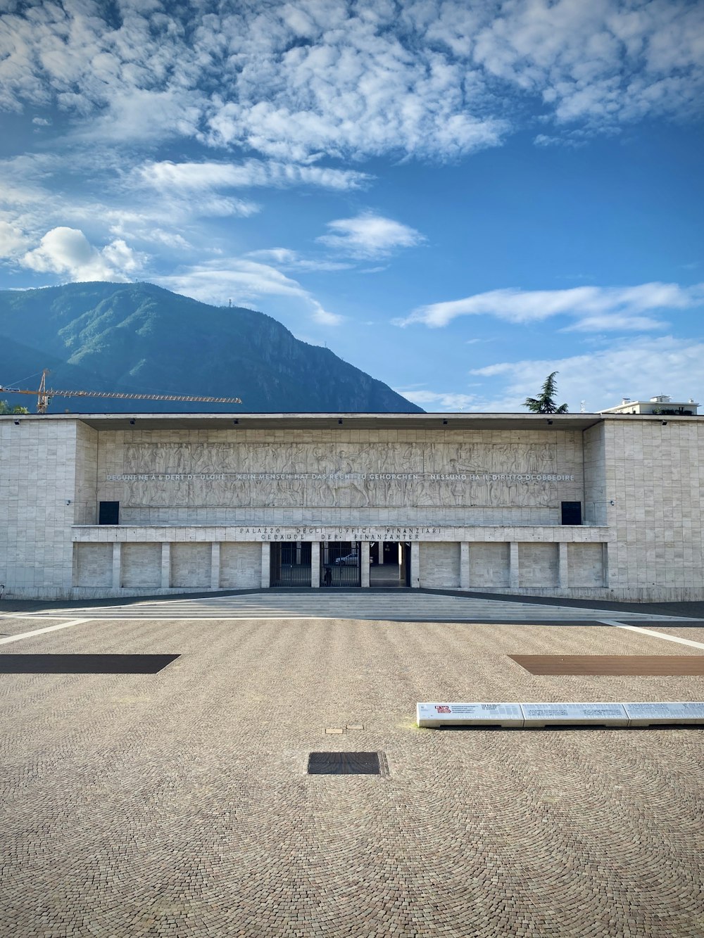 昼間の青空の下、山の近くにある灰色のコンクリートの建物