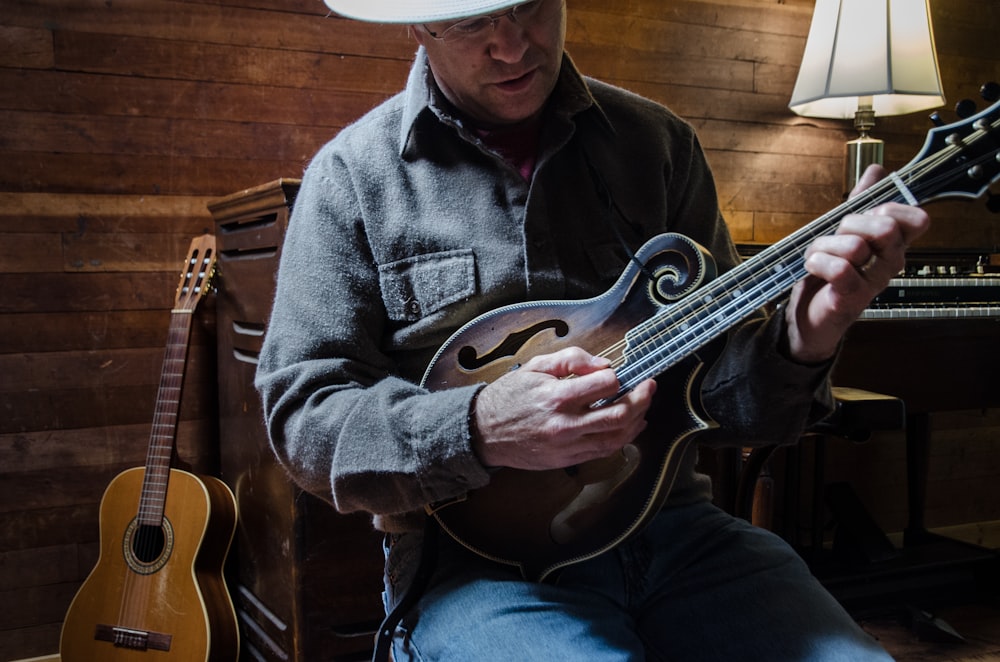 man in blue denim jacket playing brown acoustic guitar