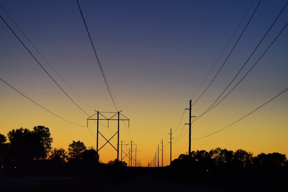 silhouette of electric post during sunset