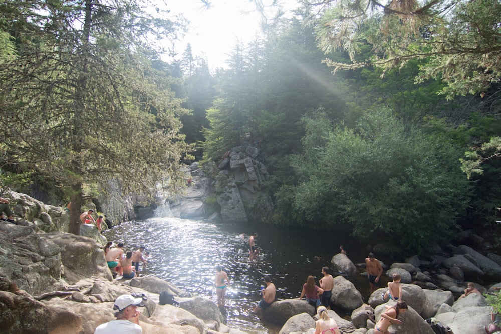 people sitting on rock in river during daytime