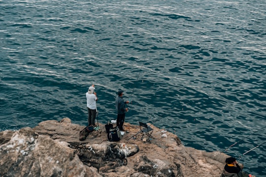 man and woman standing on rock near body of water during daytime in Boca do Inferno Portugal