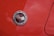 A close-up view of an emblem with the text 'Chevrolet Motor Division Corvette' featuring two crossed flags on a glossy red car surface with water droplets scattered across.