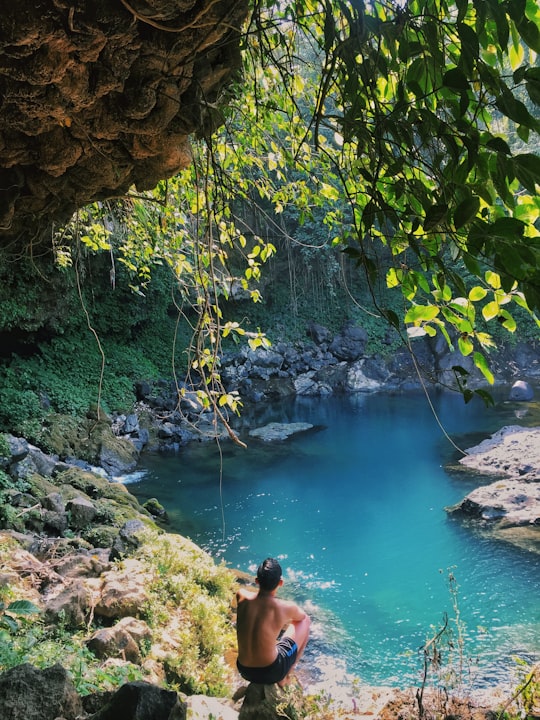 man in blue shorts sitting on rock near river during daytime in Purbalingga Indonesia