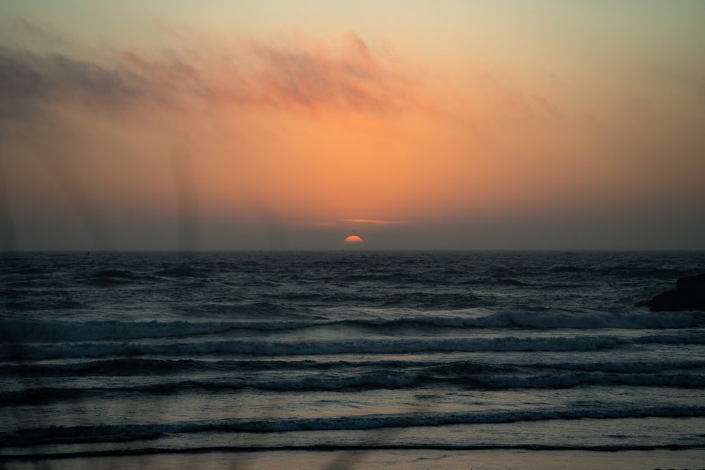 the sun is setting over the ocean with waves