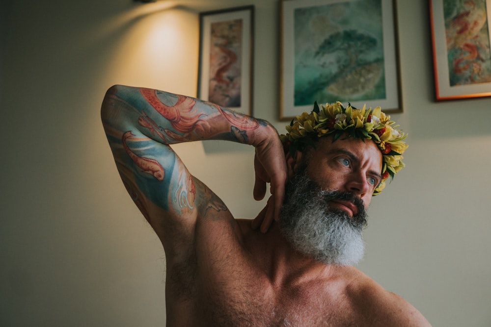 topless man with green and red floral tattoo on his right arm