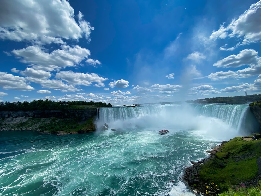 cascadas bajo el cielo azul y nubes blancas durante el día