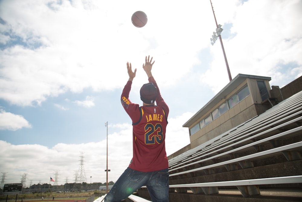 man in orange and white basketball jersey shirt and blue denim jeans jumping on air