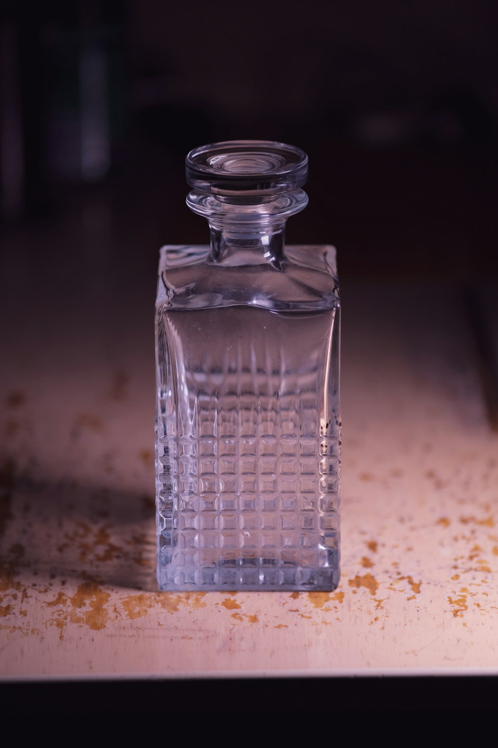 clear glass bottle on brown marble table