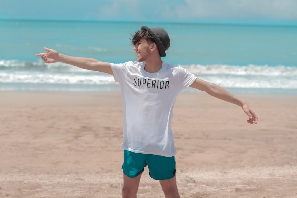 woman in white crew neck t-shirt and blue shorts standing on beach during daytime