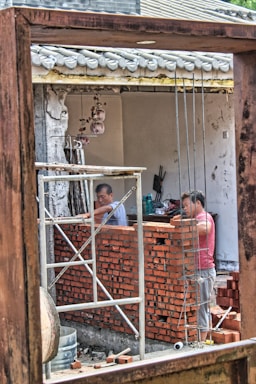 man in red and white stripe shirt standing in front of brown wooden door