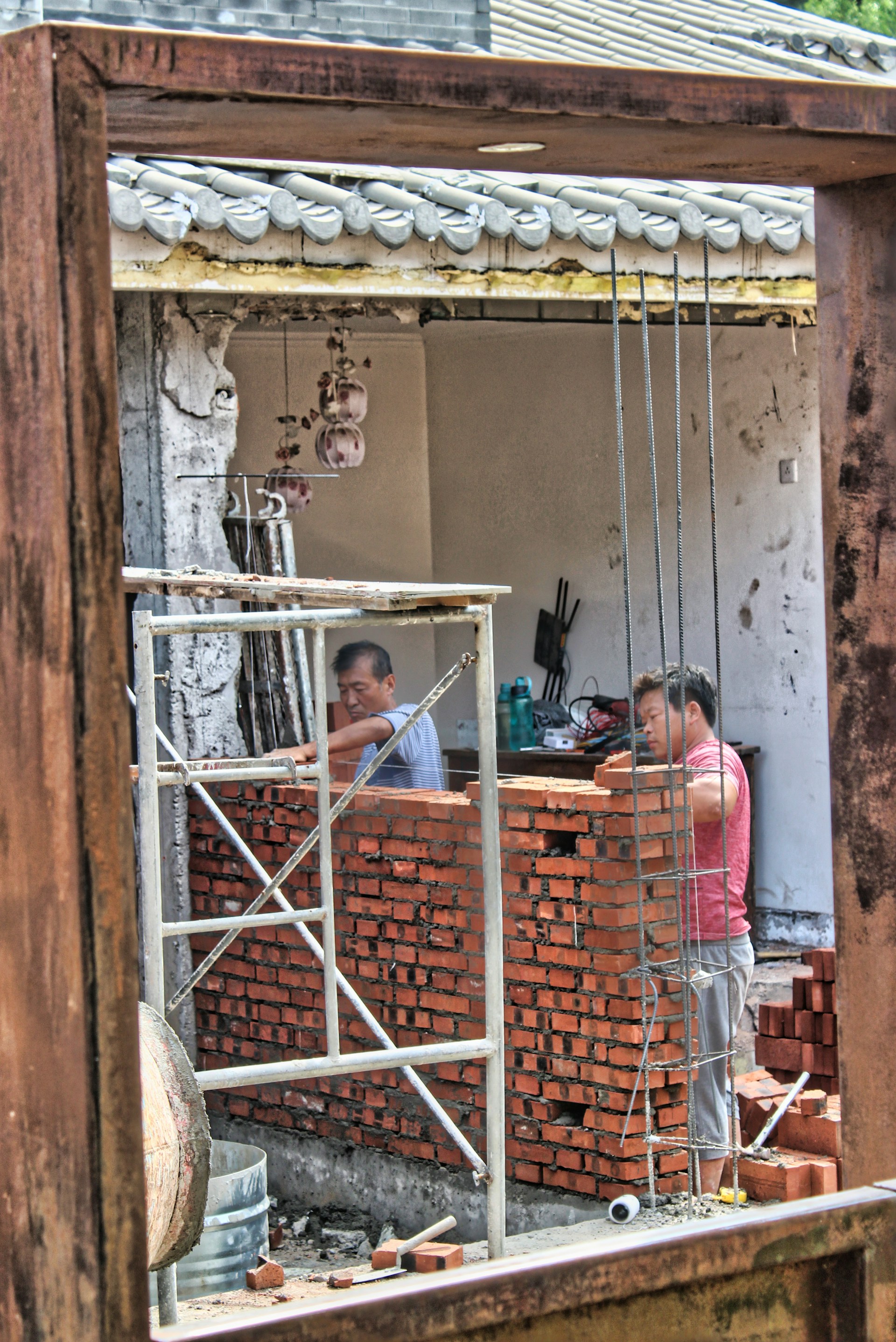 man in red and white stripe shirt standing in front of brown wooden door