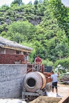 Construction workers laying bricks on a sturdy house foundation in a suburban neighborhood.