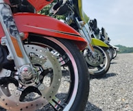 A lineup of diverse motorcycles parked side by side on a gravel path.