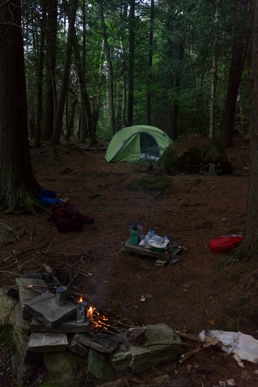 a tent in the woods with a campfire in the foreground
