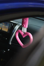 A woman happily using a pink-themed electronic kit inside her car.