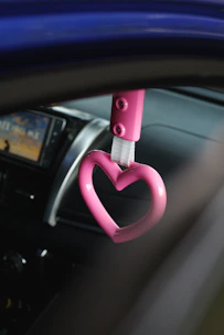 A woman happily using a pink-themed electronic kit inside her car.