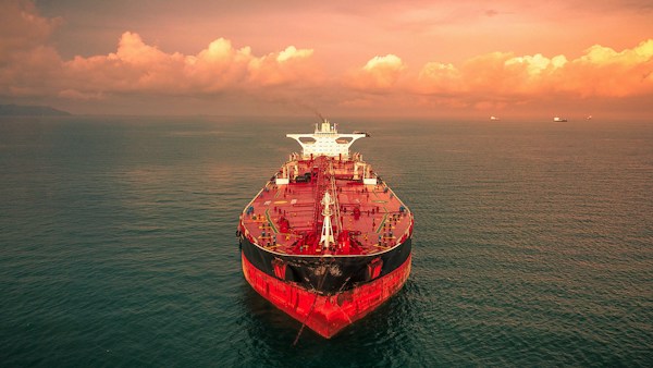 A crude oil tanker at sea under an orange evening sky