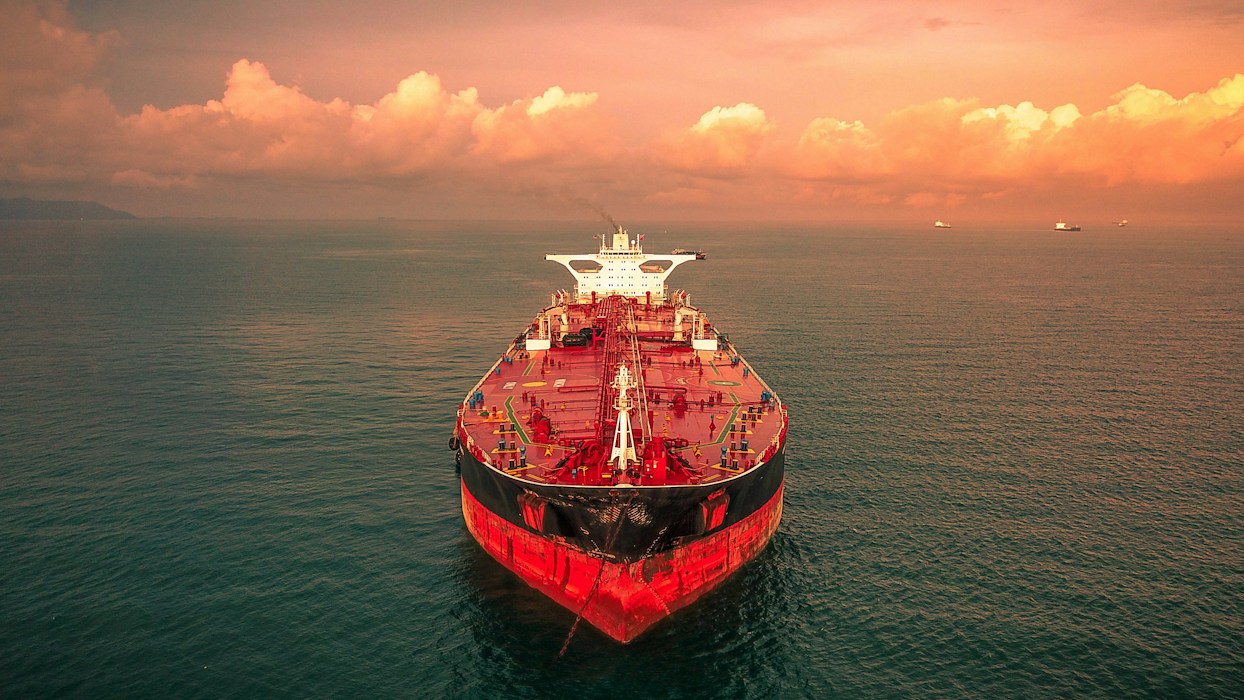 A crude oil tanker at sea under an orange evening sky