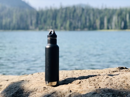 Sports bottle on sand near water
