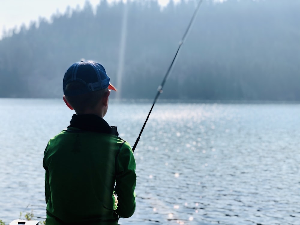 man in green hoodie fishing on lake during daytime