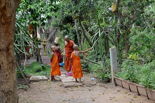 2 boys in orange robe walking on pathway during daytime