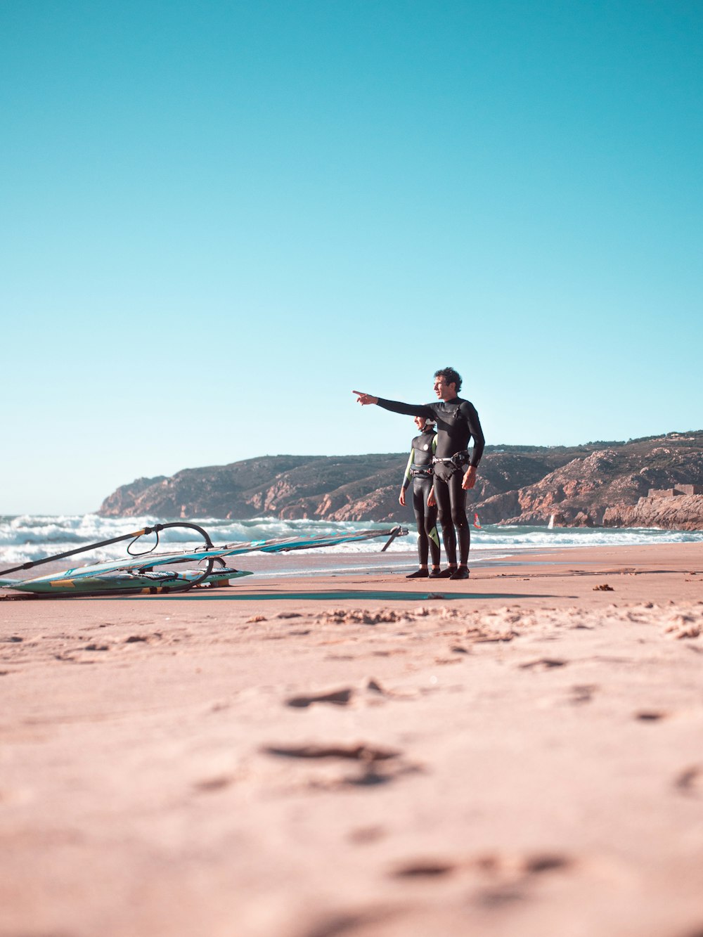 man in black jacket standing on beach shore during daytime