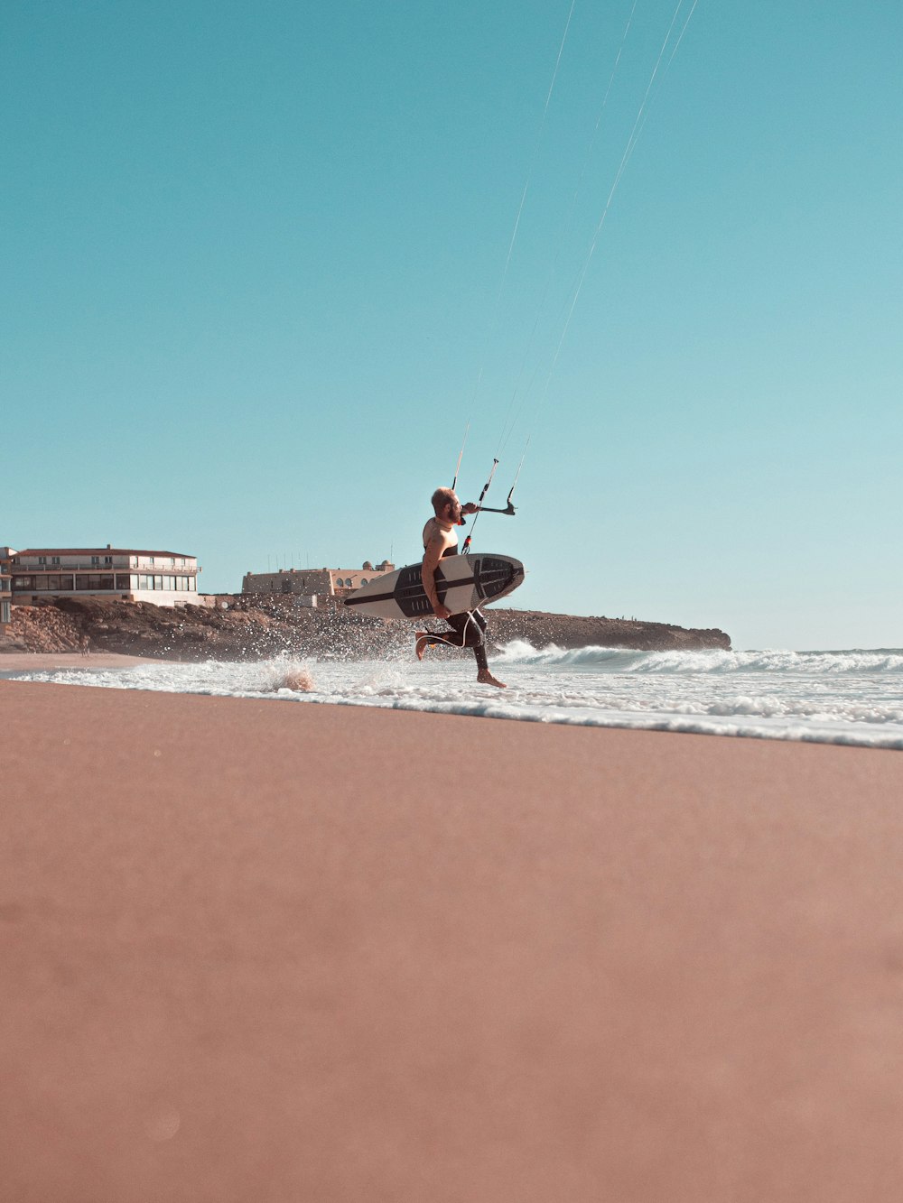 man in red shirt and black shorts riding on a surfboard on a beach during daytime