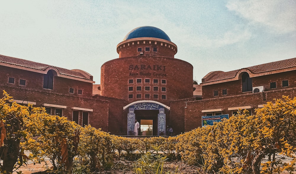 brown brick building surrounded by green plants