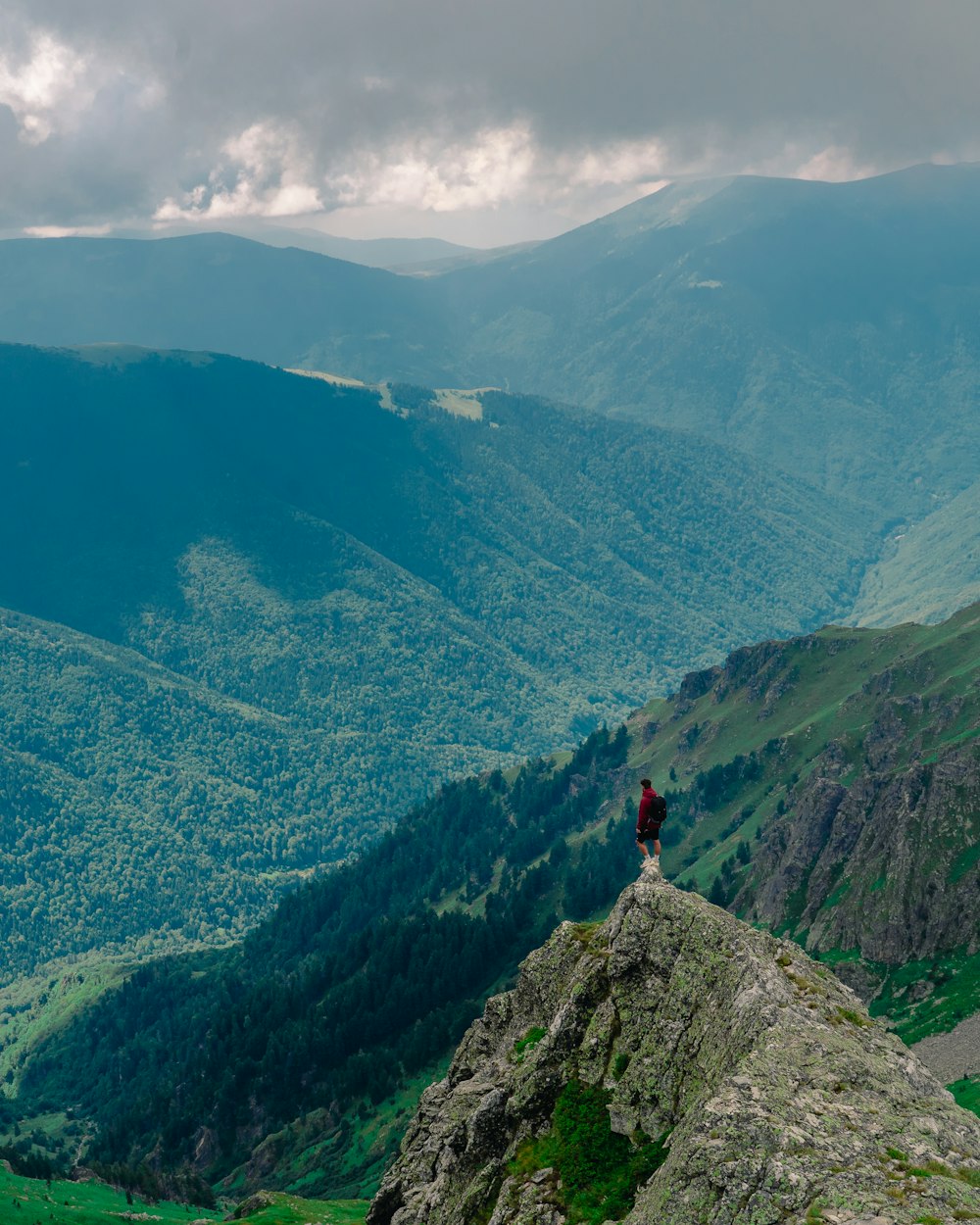 person in red jacket standing on rock mountain during daytime