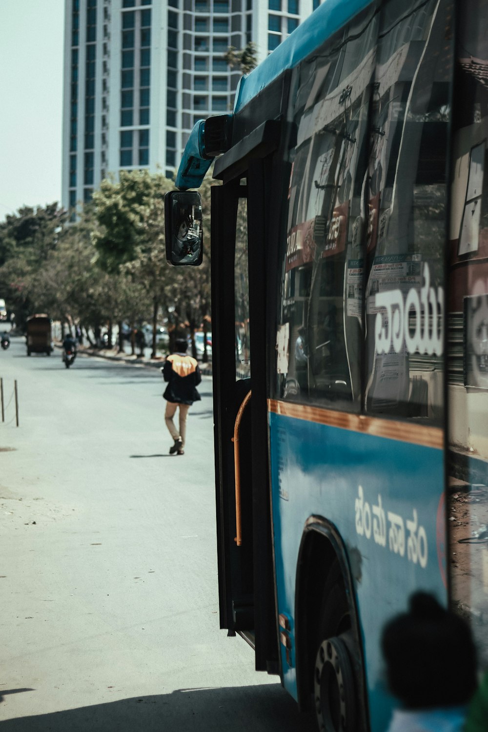 검은 셔츠와 검은 반바지를 입은 여자가 낮에 파란색과 흰색 버스 옆에 서 있다