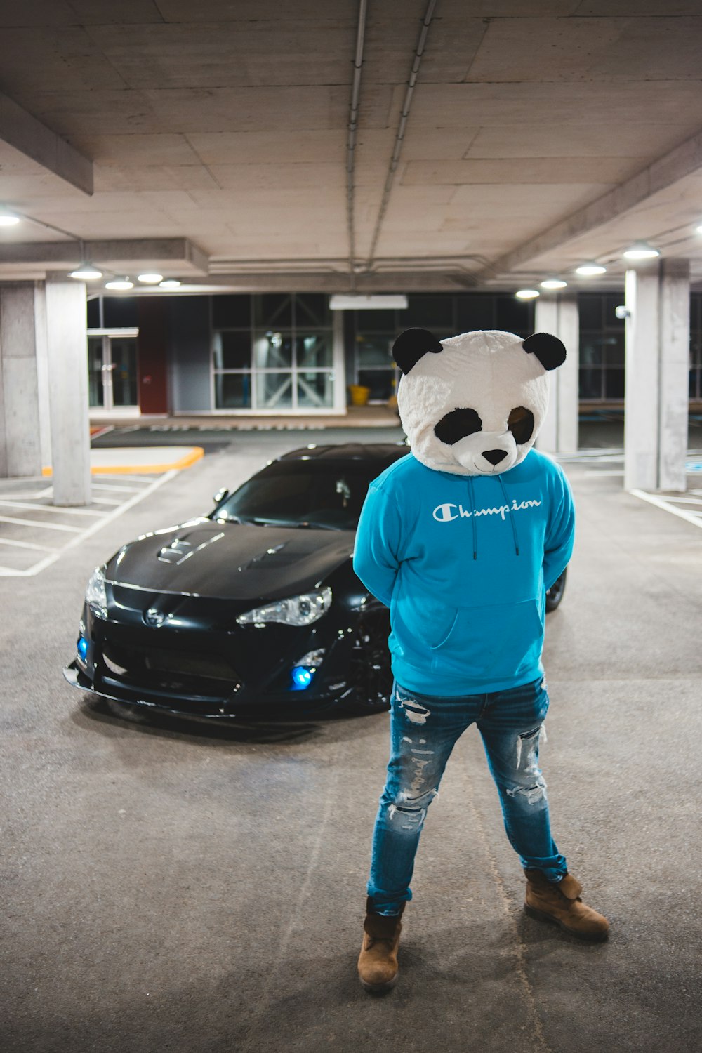 person in blue and black panda hoodie standing beside black car