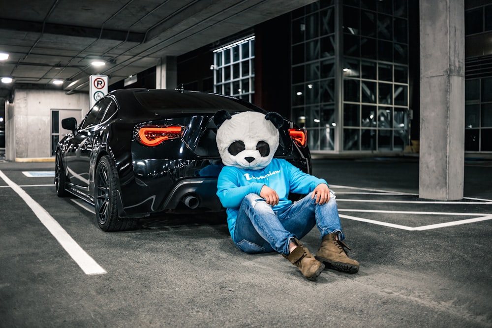 man in blue denim jeans sitting on black car