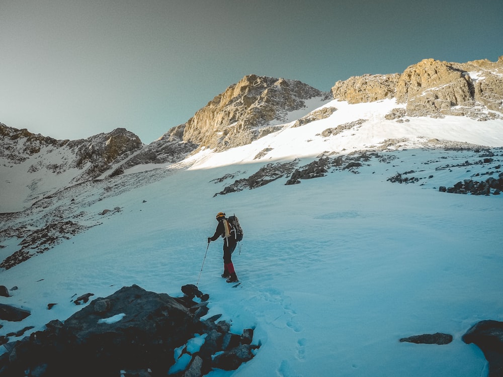 man in black jacket and blue denim jeans standing on snow covered ground during daytime