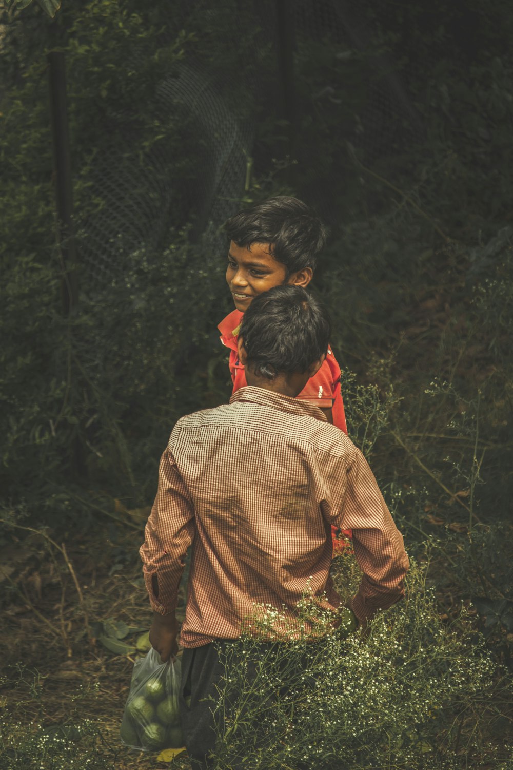 man in brown and white checkered dress shirt standing in forest during daytime